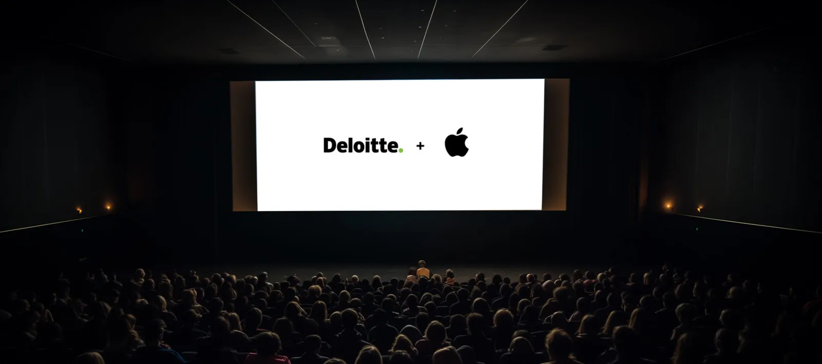 A packed auditorium facing a screen showing the Deloitte and Apple logos.